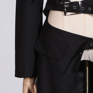 Detail of waist cutout and thick belt with metal buckle on black trench coat