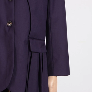 Detail view of deep purple trench coat with brown button and pleated skirt hem design