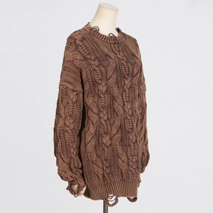 Detail of chunky cable knit texture with distressed ripped hem on brown sweater