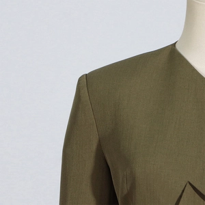Detail shot of the V-neckline and structured shoulder of an olive green women's blazer