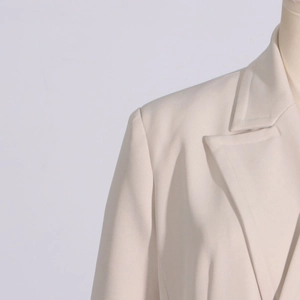 Detail view showing shoulder cut and lapel design of the off-white trench coat jacket
