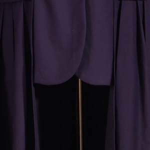 Detailed close-up of dark purple trench coat fabric with elegant draped pleats and texture