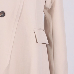 Detail of beige trench coat showing marble button and neat pocket stitching