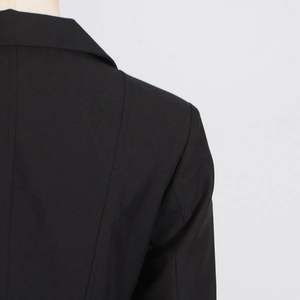 Detailed close-up showing the premium textured fabric and tailoring on black trench coat