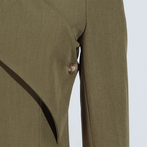 Detail of olive green blazer showing marble-textured button and layered overlap design