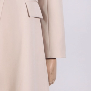 Detail of pale pink trench coat featuring flat woven fabric and a flap pocket design