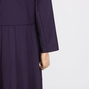 Detail of plum purple dress showing high-waisted tailoring and pleated skirt texture