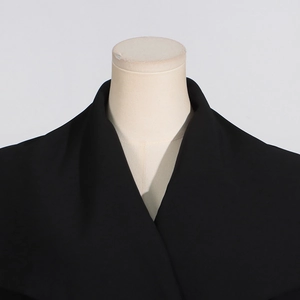 Detailed close-up of high-quality black trench coat lapel on a neutral mannequin