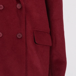 Détail macro d'un manteau en laine bordeaux montrant les boutons et la poche à rabat
