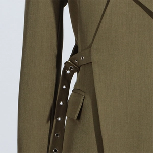 Detailed macro view of olive green blazer with metal eyelet belt and flap pocket detail