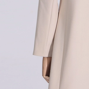 Detail of beige trench coat sleeve and side cut on a wooden mannequin stand