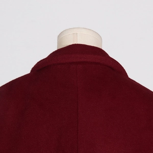 Vue détaillée du col du manteau en laine bordeaux et de la texture du tissu épais