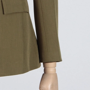 Detailed close-up of olive green blazer pocket and stitching craftsmanship on fabric
