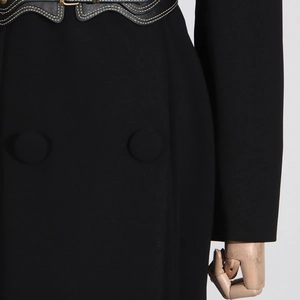 Detail of waist corset with scalloped edges and contrast stitching on a black trench coat
