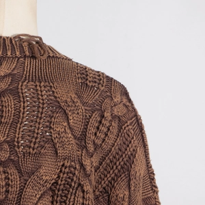 Close-up of deep brown chunky knit sweater showing classic cable stitch texture and neckline