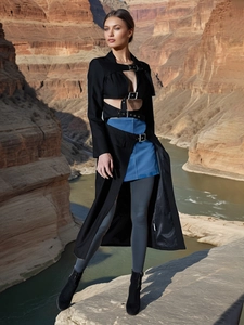 Long black cutout trench coat with metal buckles on cliff edge backdrop for women