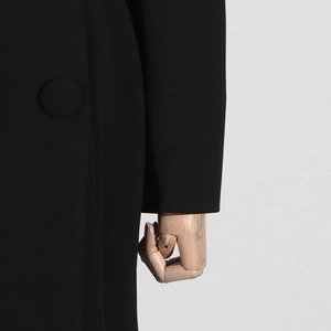 Detailed close-up of a premium black coat featuring elegant fabric and a matching cloth button
