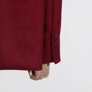 Détail macro du poignet d'un manteau en laine bordeaux avec trois boutons assortis