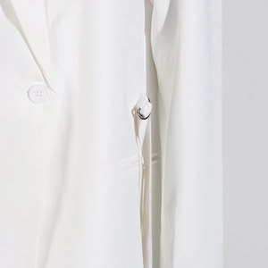 Détail d'une robe blazer blanche avec bouton en résine et boucle de ceinture en D