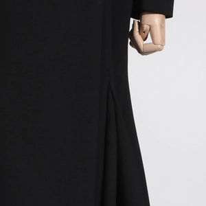 Detail view of the black trench coat featuring 3D pleated design and smooth fabric texture