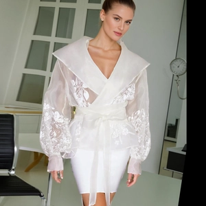 Detailed view of floral embroidery on a white sheer lantern sleeve wrap blouse