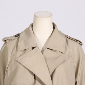 Dettaglio del colletto di un trench beige in stile britannico con spalline e cuciture