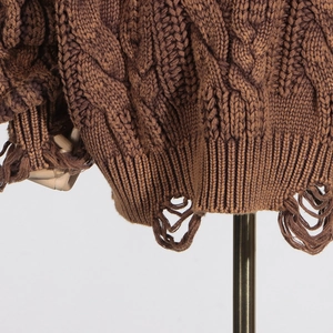 Detail of cable knit pattern and distressed hem on brown oversized sweater