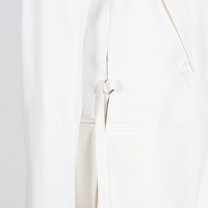 Détail d'un blazer blanc avec boucle en D argentée et finition de poche passepoilée