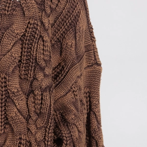 Detailed close-up of dark brown cable knit pattern and texture on a chunky sweater