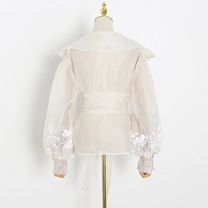Back view of a sheer white floral blouse featuring lantern sleeves and a waist tie