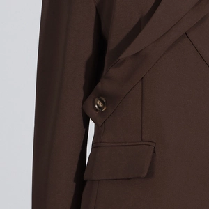 Détail du blazer marron foncé avec col croisé unique et bouton ambré texturé