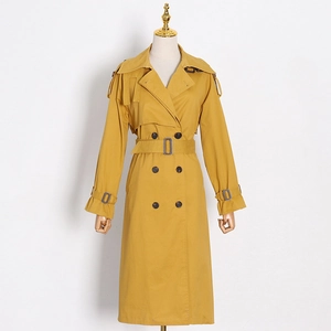 Detail view of mustard trench coat featuring double-breasted buttons and adjustable waist belt
