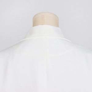 Détail de la robe blazer blanche montrant les coutures du col et le tissu tissé chic