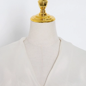 Detail of elegant cream v-neck satin blouse neckline with subtle pearlescent finish