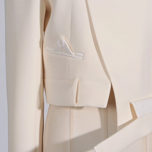 Detail view of cream tailored blazer showing decorative faux pocket and white button