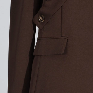 Détail de blazer marron foncé avec bouton texturé, poche à rabat et coutures
