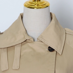 Detailed close-up of khaki trench coat collar with epaulettes and tortoiseshell buttons