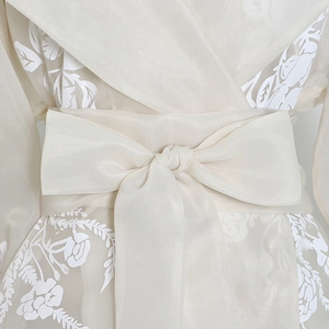 Detailed view of semi-transparent organza fabric with floral embroidery and waist tie
