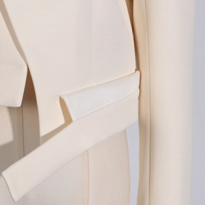 Detail of cream blazer showing structured fabric texture and decorative side strap design