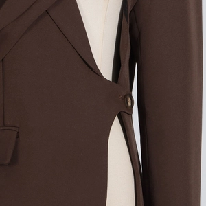Détail de la veste de tailleur marron foncé avec découpe à la taille et fermeture à bouton