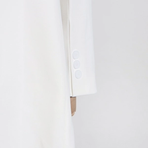 Vue détaillée du poignet d'une robe blazer blanche avec trois boutons mats