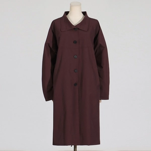 Detail view of deep wine red long trench coat with classic lapels and single-breasted buttons