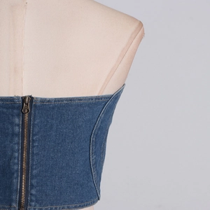 Dettaglio top a fascia in denim blu con doppie cuciture arancioni e cerniera metallica