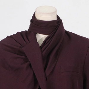 Detail of wine red trench coat showing lapels, decorative pocket, and matching scarf