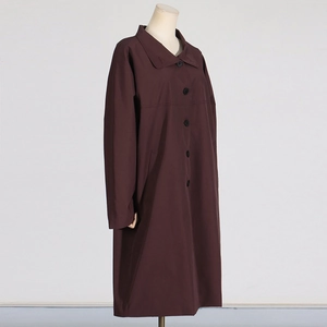 Detail of dark coffee long trench coat showing single-breasted buttons and side pocket