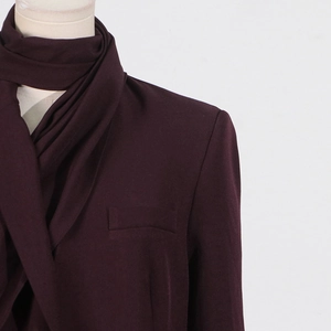 Detail of burgundy blazer featuring elegant scarf collar and professional shoulder tailoring