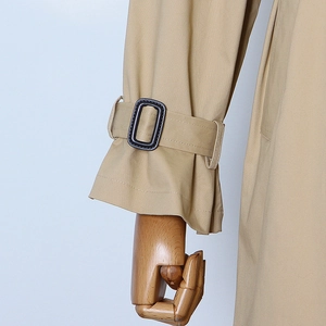 Detail of camel trench coat sleeve featuring adjustable cuff strap and buckle on a mannequin