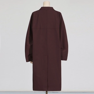 Detail view of the back of a burgundy long trench coat showing lapels and middle slit design