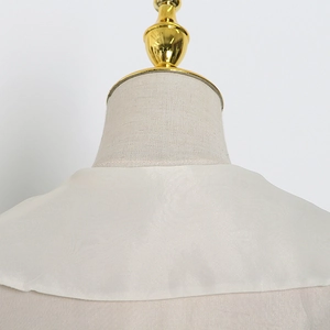 Detail of elegant beige blouse featuring a large Peter Pan collar and pearly texture fabric