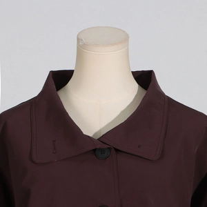 Detail view of lapel collar and resin buttons on dark brown long-sleeved trench coat